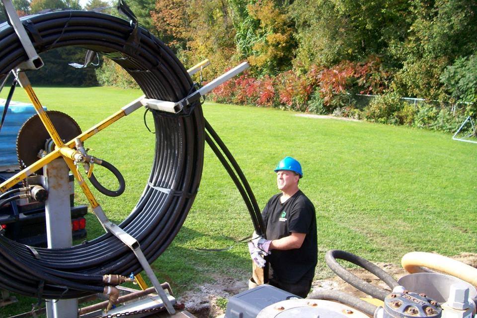 GDNE crew laying HDPE geothermal pipe into manifold trenches connecting vertical boreholes